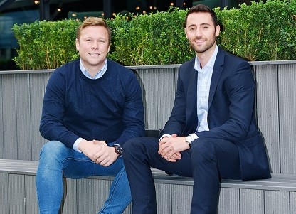 Two men sitting outside on a grey wooden bench.