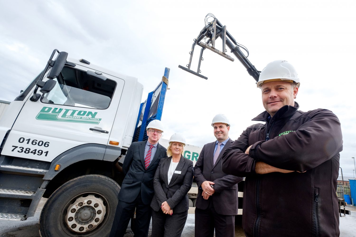 Four people wearing hard hats outside next to a truck. There is a woman in the group.