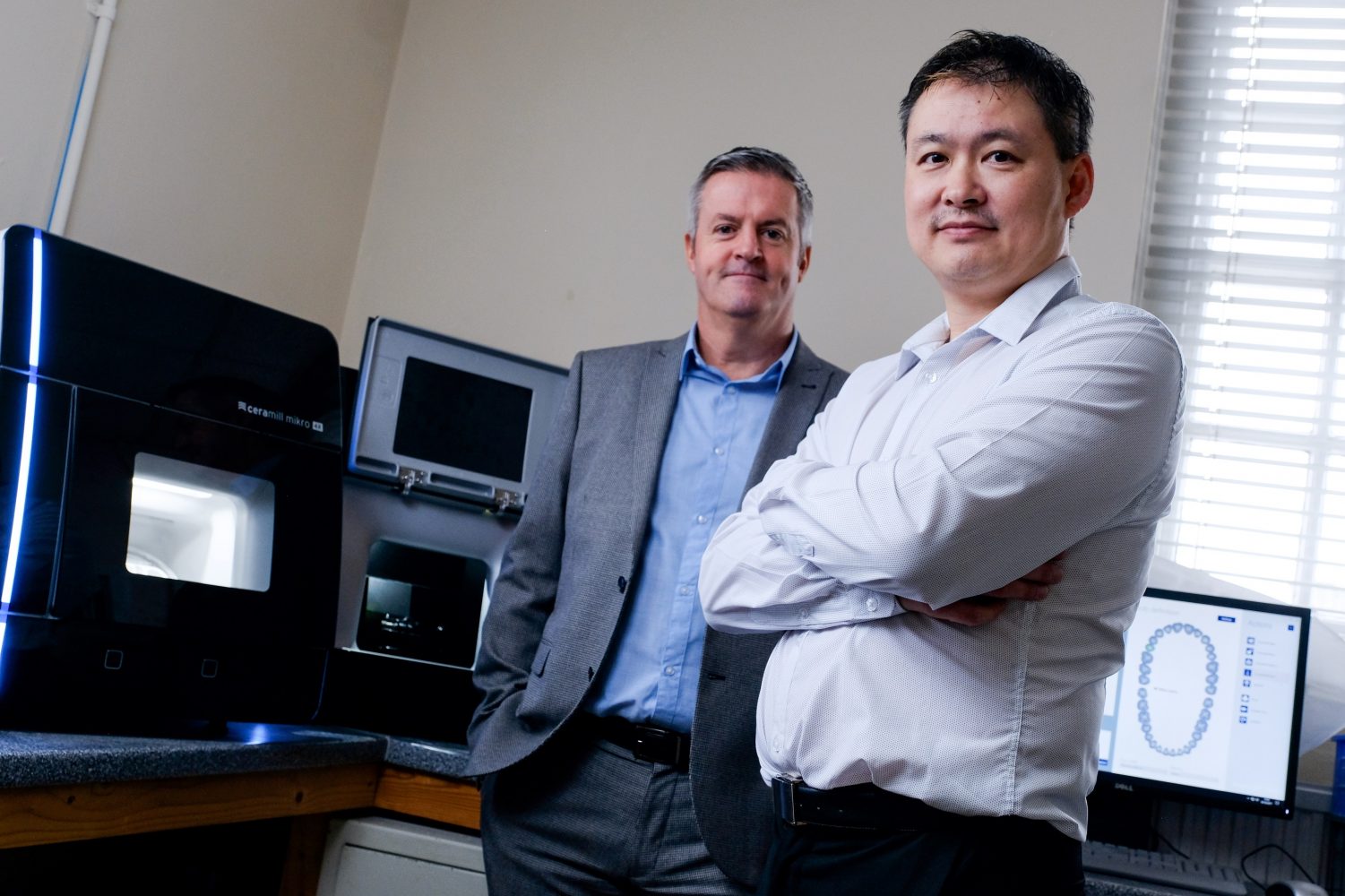 Two men in an office surrounded by IT equipment.