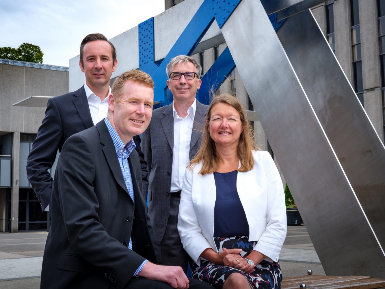 3 men and a woman from Cress Systems smiling outside the office building