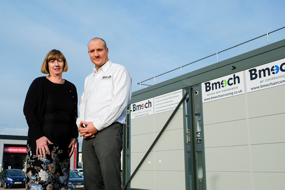 Man and woman outside to the left of Bmech equipment.