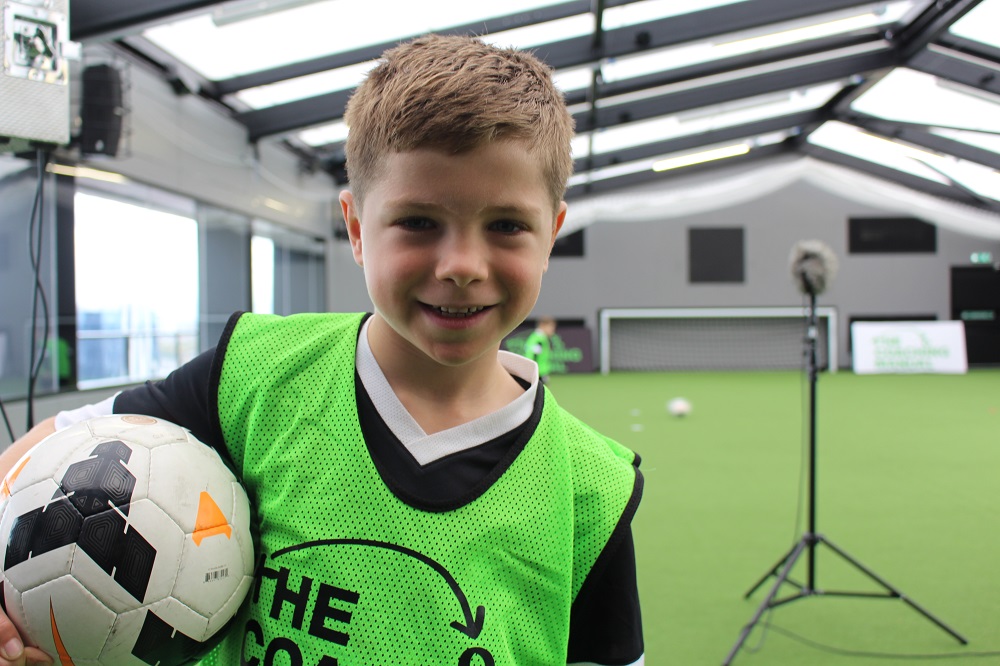 Young boy holding a football in a sports stadium.