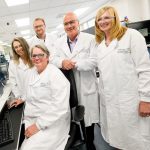 5 people in a lab wearing lab coats