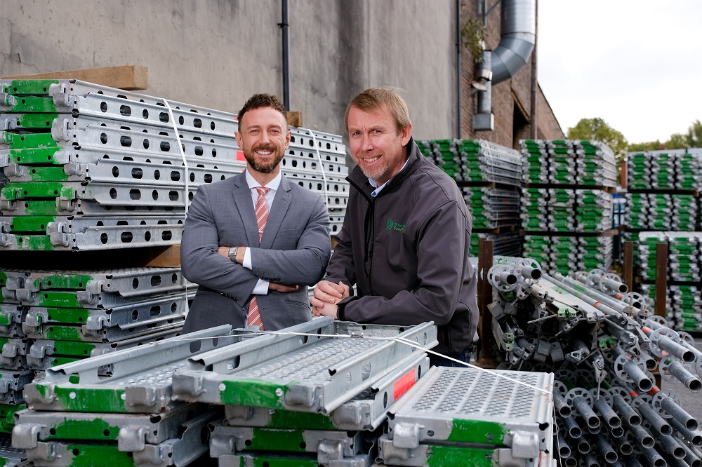 Two men outside surrounded by scaffolding.