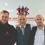 3 men stood in front of a fire safety logi