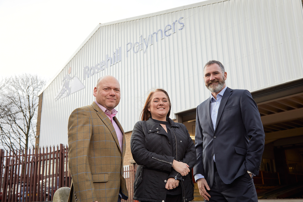 One man to the left wearing a beige suit, woman in the middle wearing black jacket and man to the left wearing a black suit outside Rosehill Polymers factory.