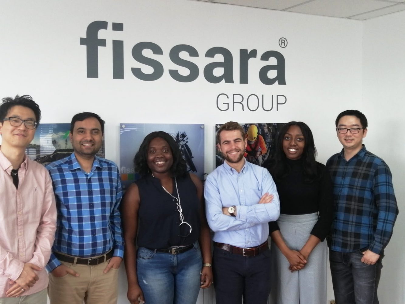 A group of employees stood in front of a Fissara group branded wall