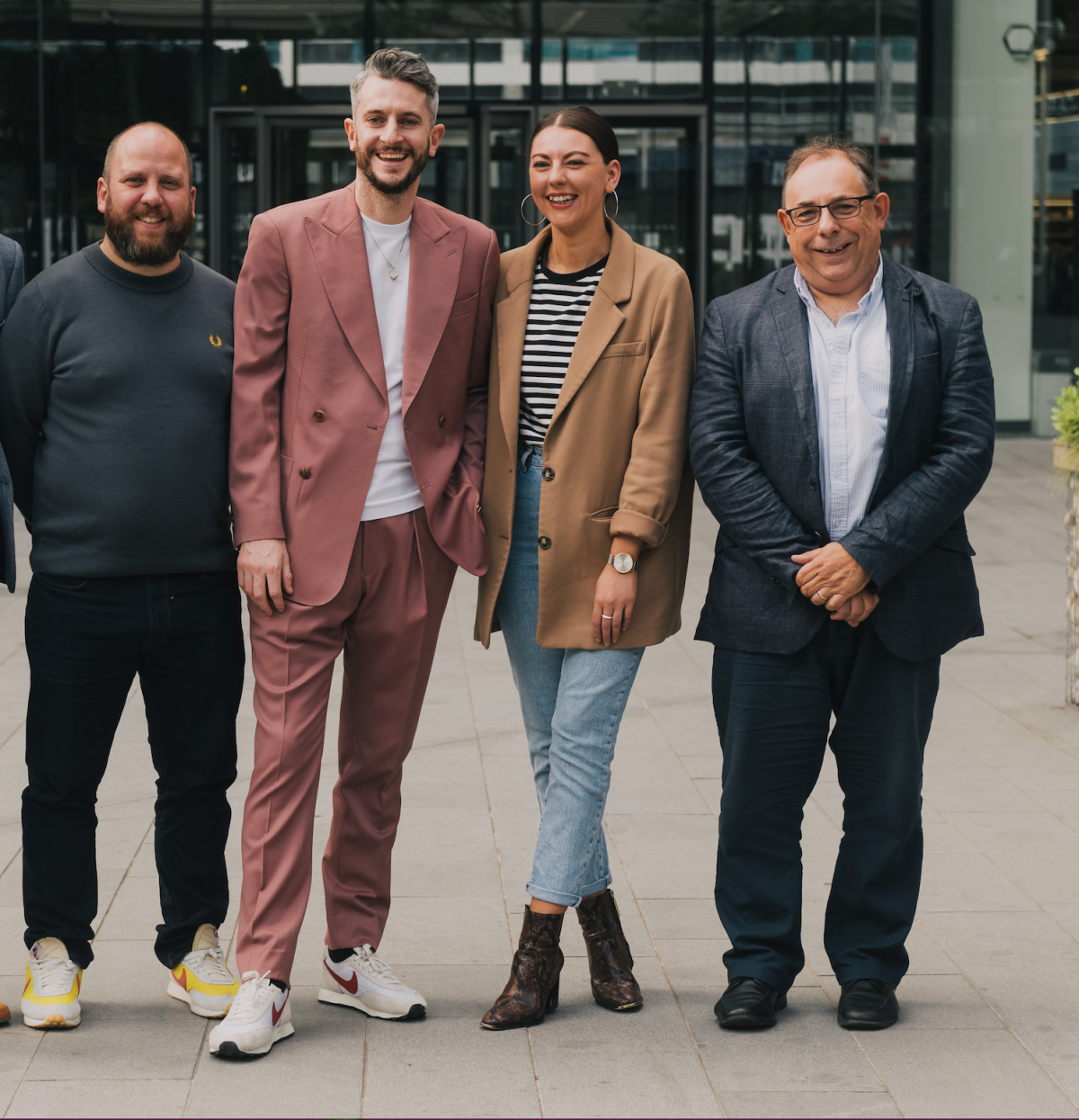 3 men and a woman stood outside an office building smiling