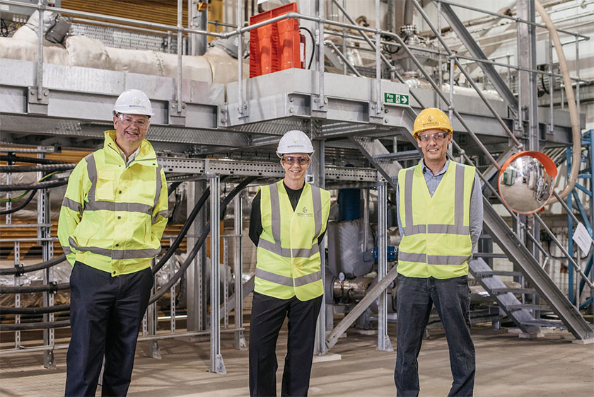 3 men in Hi Vis jackets and hard hats stood inside a biofuel plant