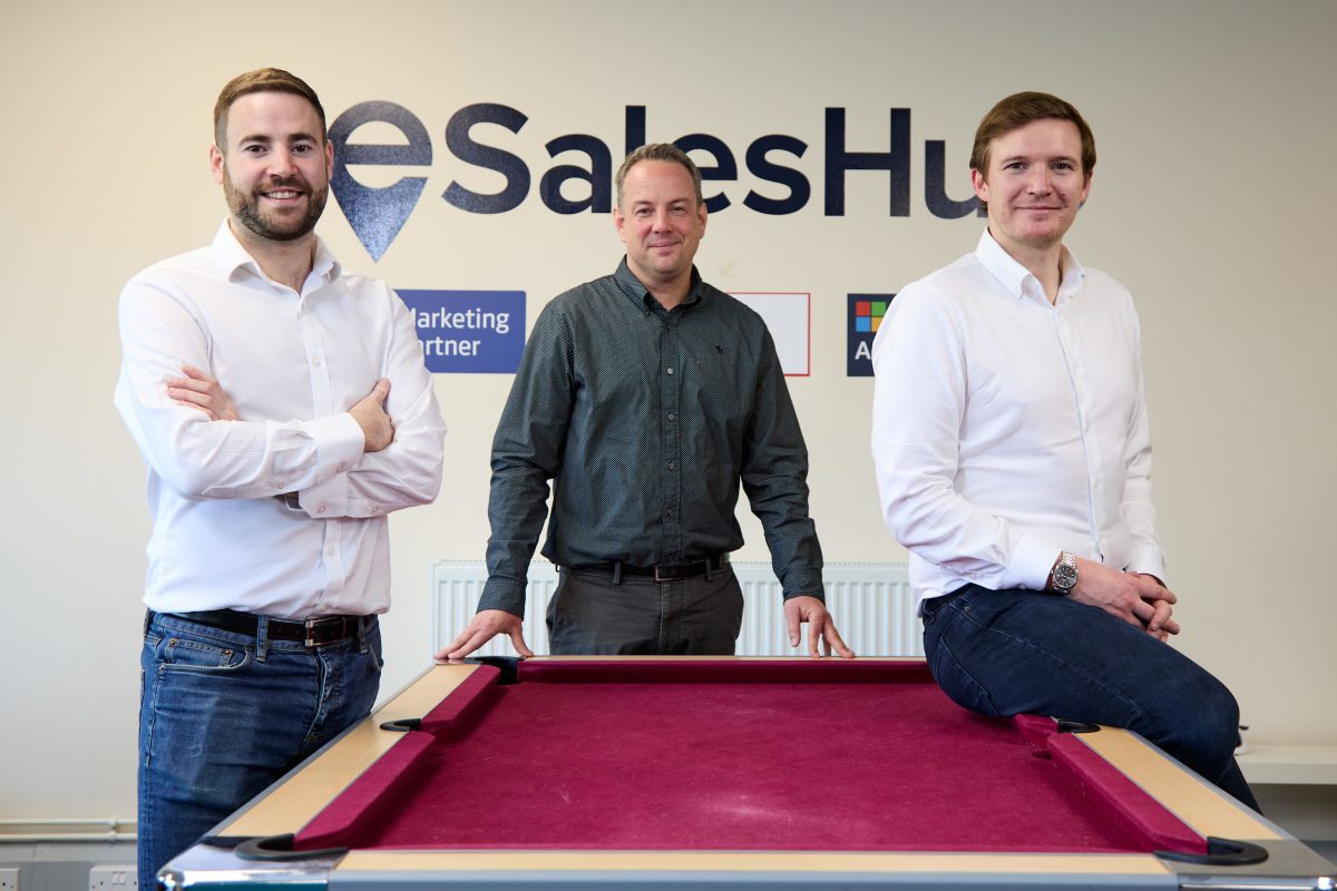 3 men sat stood around a pool table